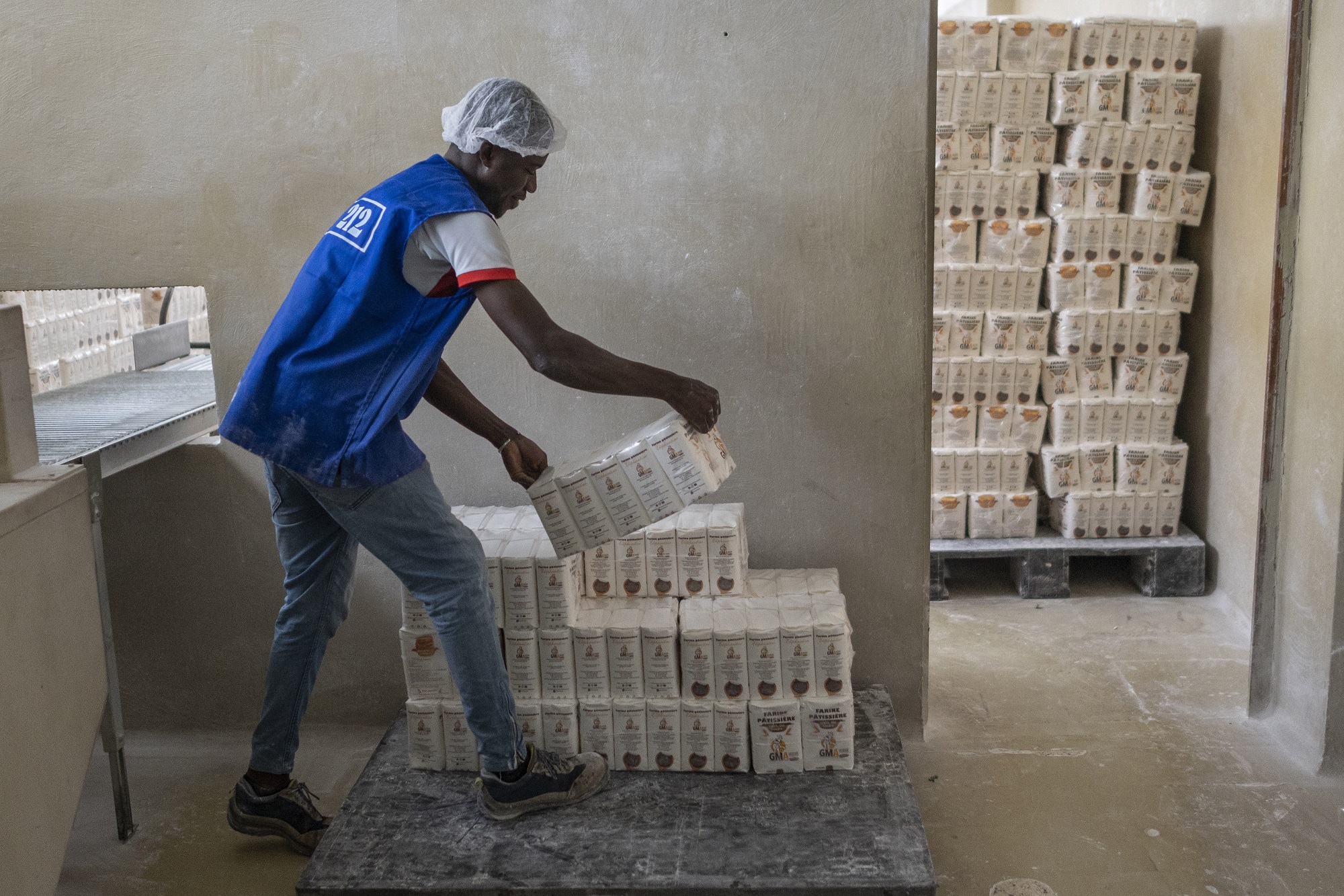 A worker stacks bags of flour for shipping at the Les Grands Moulins d'Abidjan (GMA) industrial flour mill next to the main port in Abidjan, Ivory Coast.