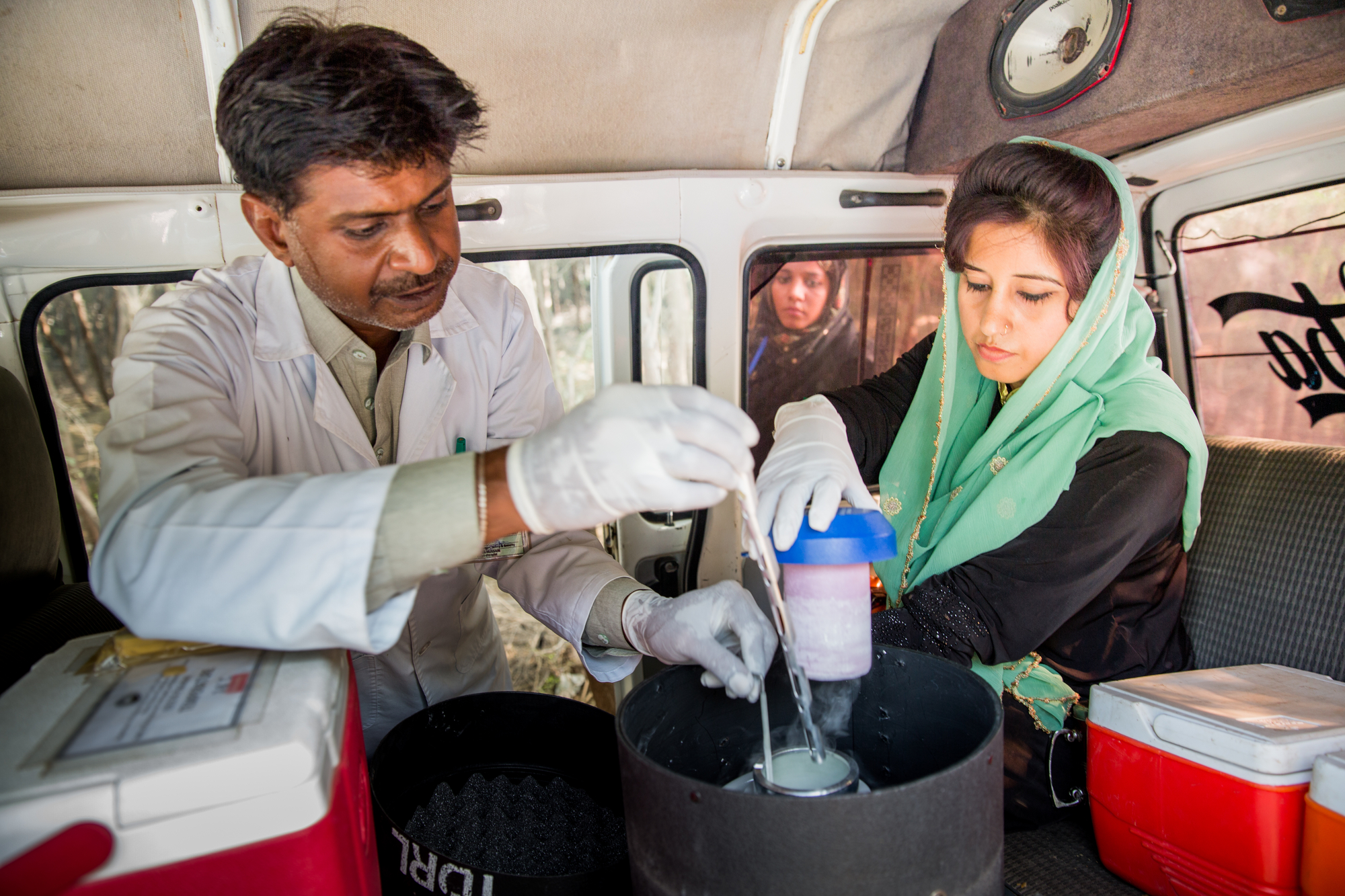 Mujeeb Hussain, and Tahira (right), research assistant, AKU (Aga Khan University) shifting stool sample of Pram Chand (6 month old) in a special storage container in the car before going to office from Akhand Jo Khoh village, Matiari district, Sindh province, Pakistan on December 1, 2016.