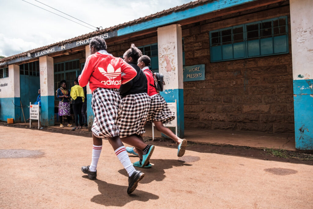 Three african teenagers linked arms and walking down the street