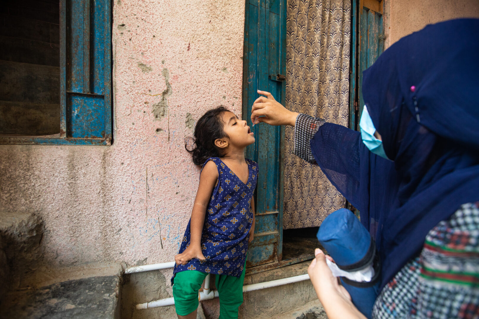 Asifa Mujahid (4.5), is immunized by polio vaccinator Naheeda Bibi (40) in Hijrat Colony, Lyari, Karachi, Pakistan