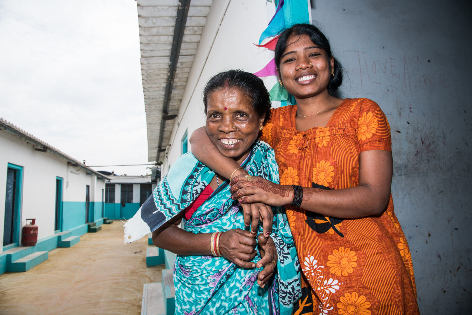 Two Tamil women, one younger and one older embrace and smile