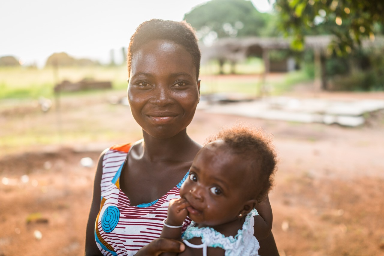 African woman smiling with a baby in her arms