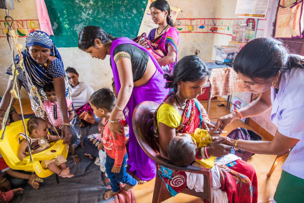 Bimla Sahu, Accredited Social Health Activist (ASHA) worker, weighs a child while Gayatri Ahirwar, Auxiliary Nurse Midwife (ANM), administers a vaccination at an Anganwadi Centre (AWC) in Bhopal, Madhya Pradesh, India on September 26, 2018.